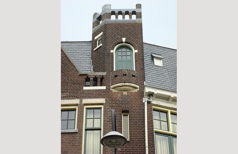 Zandsteenbeschadiging op voorgevel, de toren met het balkon.