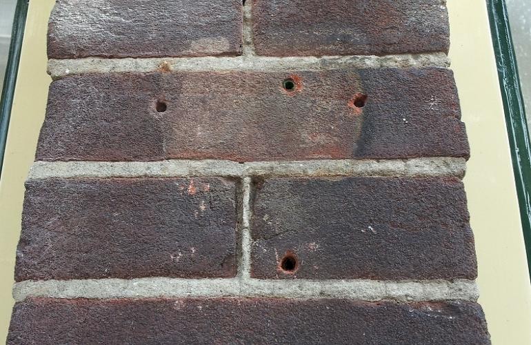 Baksteen bijkleuren, enkele gaten en verkleuring in de stenen muur.