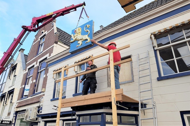 Monument met kraanmachine herplaatsen en in voorgevel inmetselen.