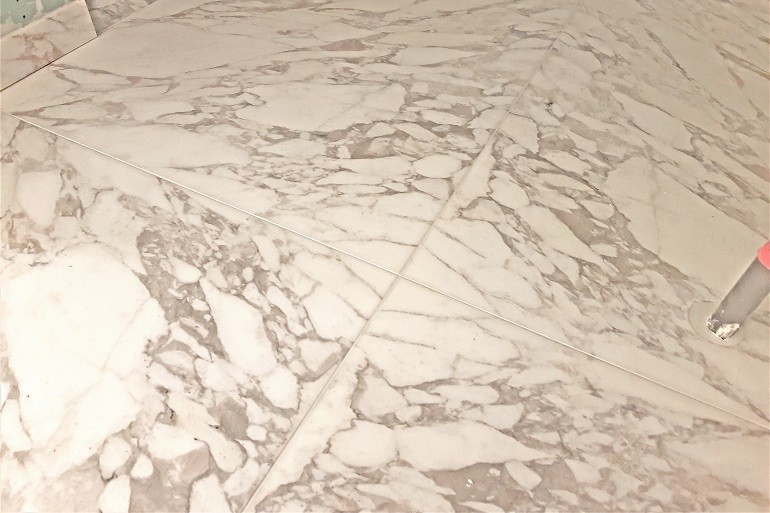 Bianco Calacatta vloerplaten in diamanten vorm op de badkamervloer.